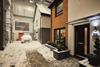 Two newly-developed homes inside a warehouse. Artificial snow is on the ground, with a car covered in the snow in front of one of the homes.
